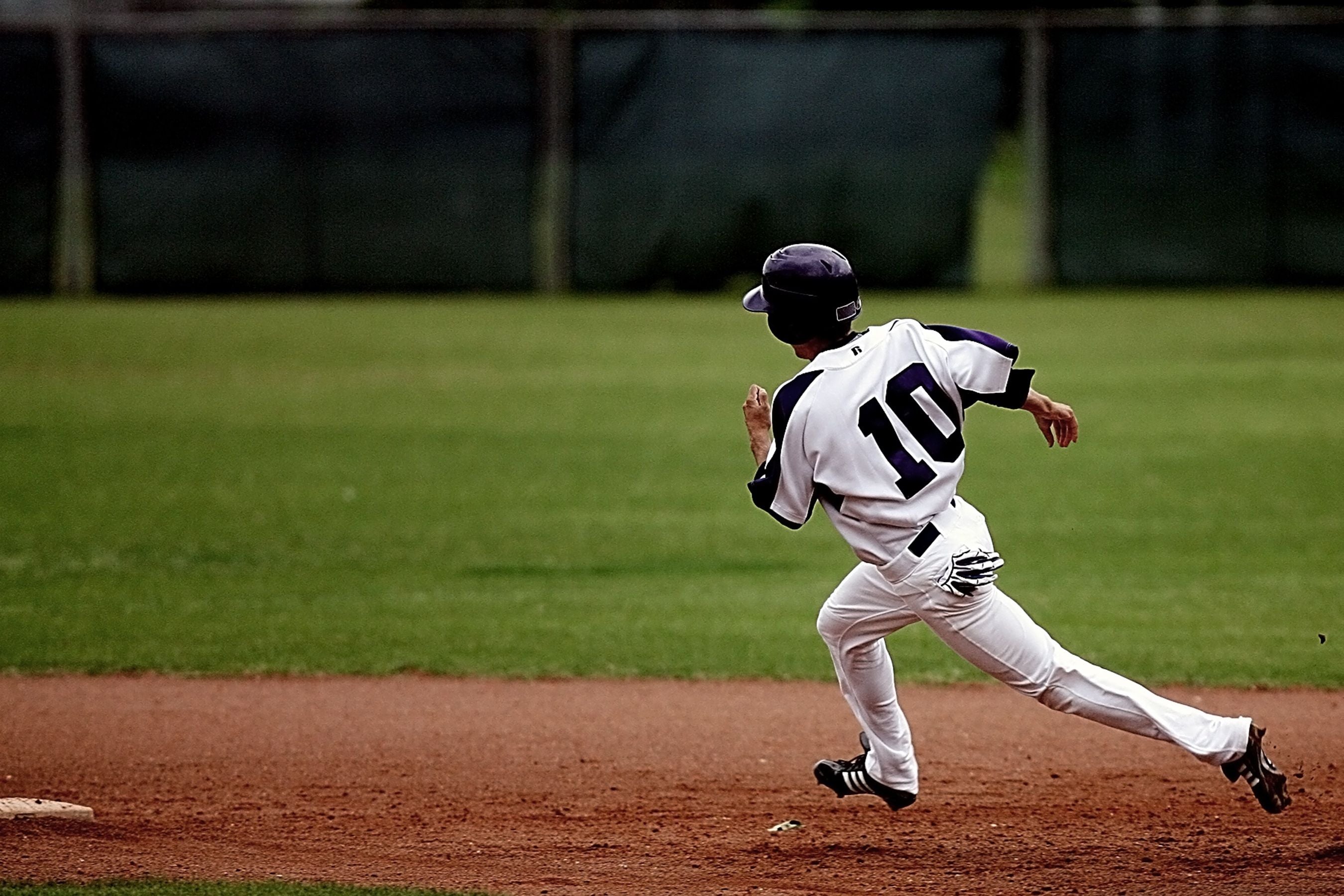 Youth baseball player rounding second base in a cloud of dust, golden evening light